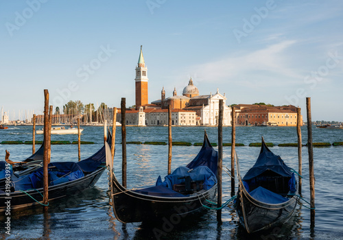 Row of gondolas moored beside the Riva degli Schiavoni against boats and San Giorgio Maggiore island, Venice, Italy © bortnikau