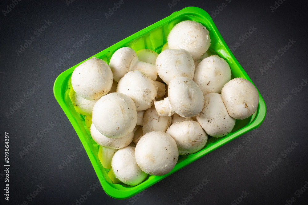 Mushrooms in packing on a dark background close up. Mushrooms in packing on a dark background close up.