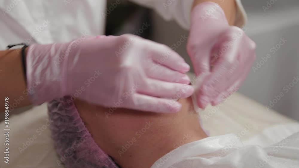 Professional beautician washes face to client with cotton pads. Professional beautician washes face to client with cotton pads.