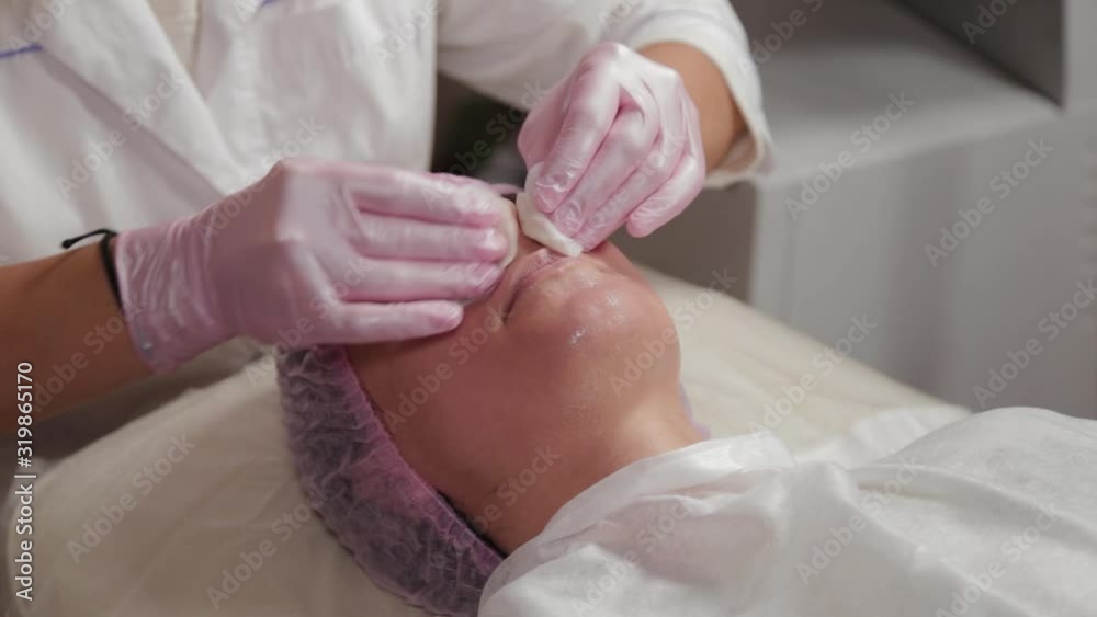 Professional beautician washes face to client with cotton pads. Professional beautician washes face to client with cotton pads.