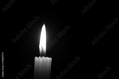 Monochrome one glowing candle on black background 