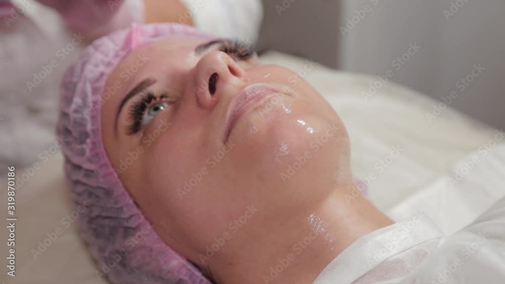 Professional beautician applying a mask on the face of the client with a brush.