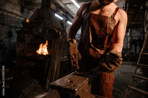Brutal bearded man craftsman, forges metal on an anvil