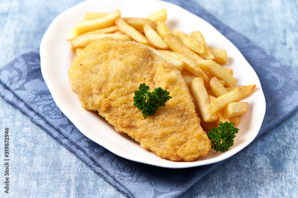 Pork Schnitzel with french fries on wooden background.