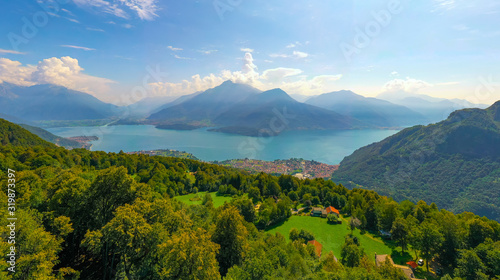 Wide Angle Panorama of Lake Como with Alps Mountains on the Background and Trees in the foreground. Travel Postcard Concept