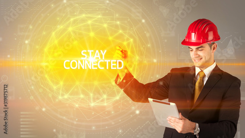 Handsome businessman with helmet drawing STAY CONNECTED inscription, social construction concept