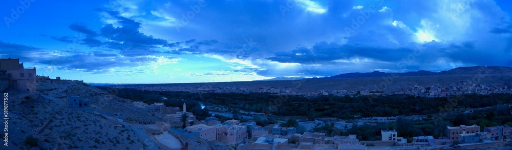 Town before green gorge with palm trees, surrounded by desert, Morocco, Africa