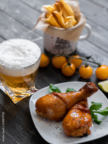 food, fried chicken drumsticks with french fries, cherry tomatoes, sauces, a beer on a plate, on a black background, serving example