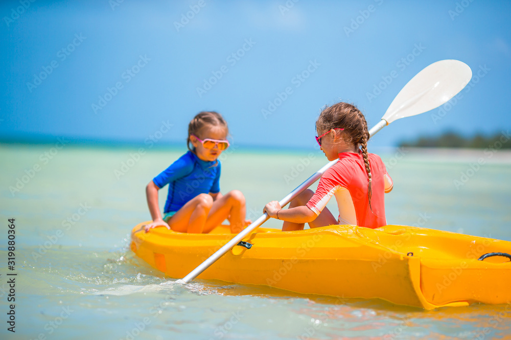 Little adorable girls enjoying kayaking on yellow kayak