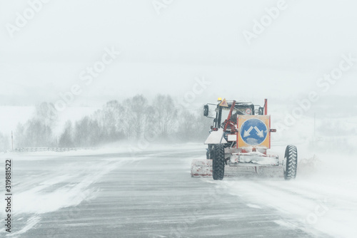 Snow removal machine on a snowy road background.