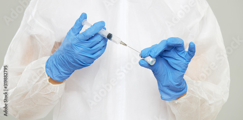 Vaccine against influenza virus, ebola, tuberculosis and other diseases. Doctors hands in protective gloves pick up an antidote in a syringe
