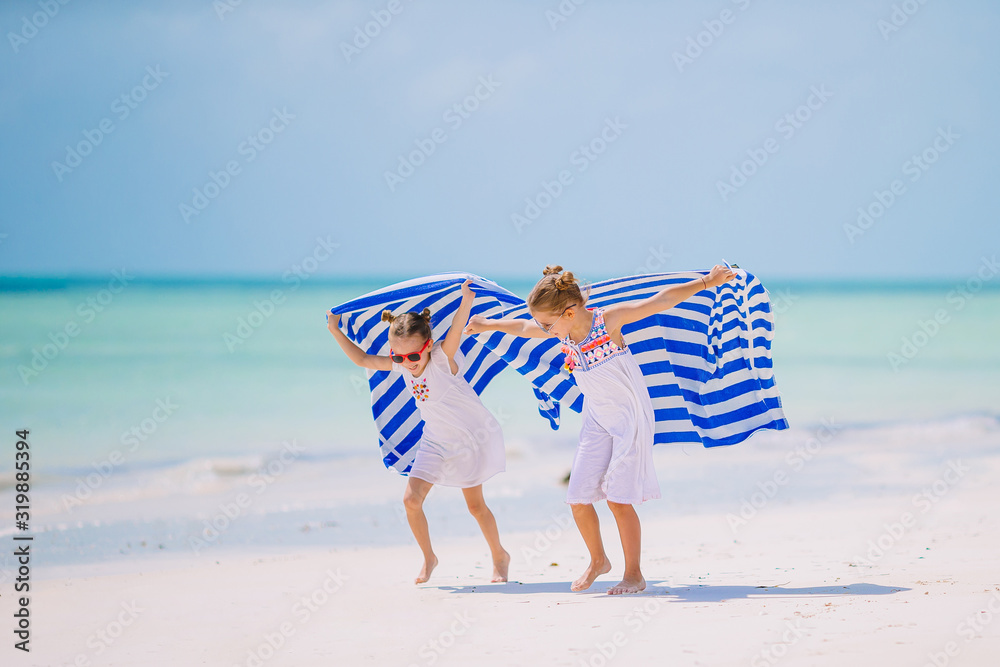 Two little happy girls have a lot of fun at tropical beach playing together Two little happy girls have a lot of fun at tropical beach playing together