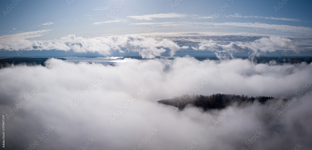 Aerial view of morning fog hovering over sunny lake