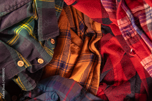 brightly colored checkered vintage flannel shirts lie together in a heap green yellow red blue orange photo