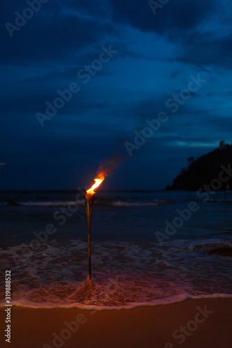 Burning torch on the sandy beach of the ocean