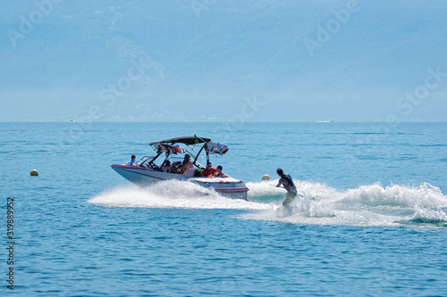 Lausanne, Switzerland - August 26, 2016: Motorboat with people aboard and man wakesurfing in Lake Geneva in Ouchy in Lausanne, Switzerland. photo