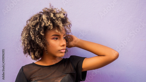 Foto Mujer joven afrodecendiente cabello risado suelto con su braso levantado mostran