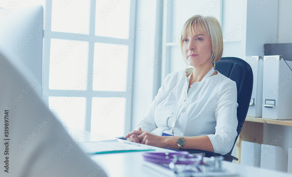 Portrait of young female doctor sitting at desk in hospital Portrait of young female doctor sitting at desk in hospital