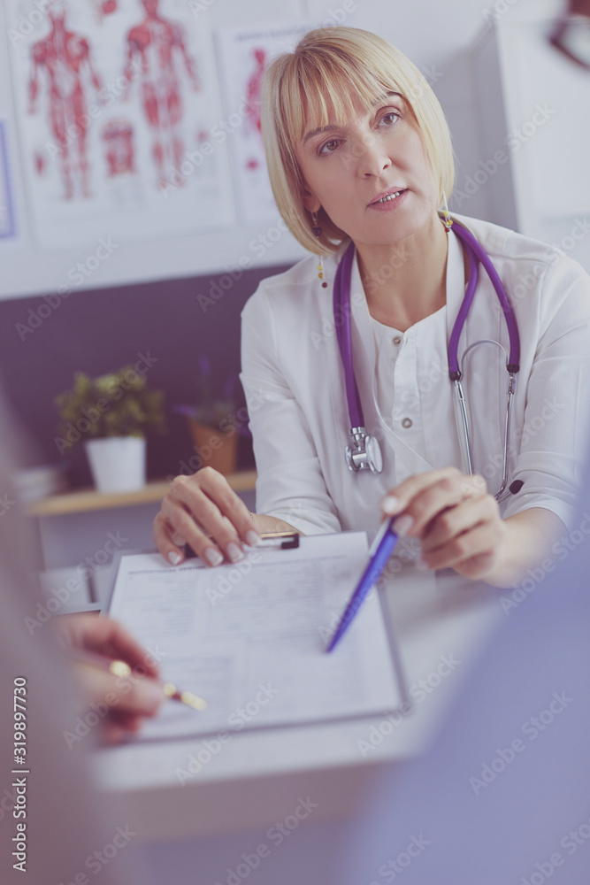 Doctor and patient examining a file with medical records, she is sitting on a wheelchair Doctor and patient examining a file with medical records, she is sitting on a wheelchair