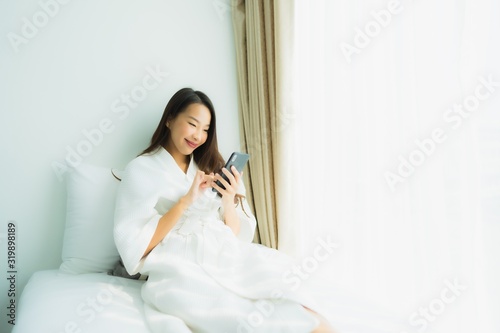 Young asian woman using mobile smart phone on bed