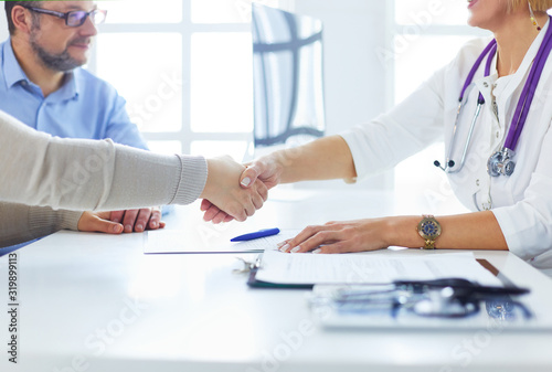 Female doctor shaking a hand in her office