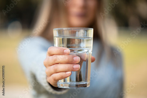 woman extending a glass of water for healthy life