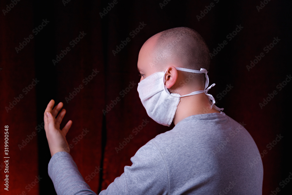 Profile of a man in medical gauze mask standing on dark red background ...
