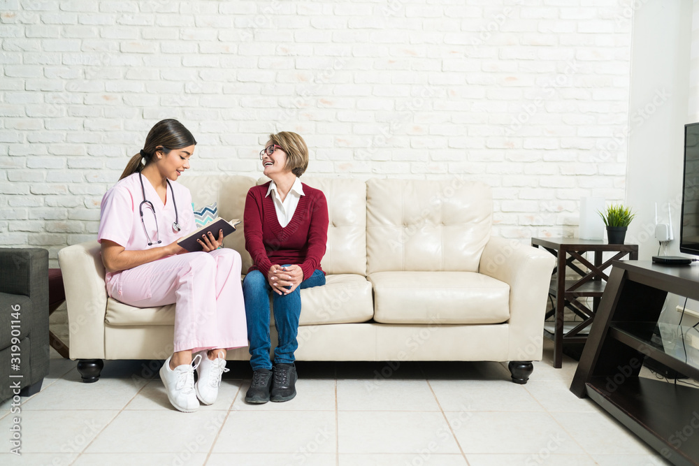 Caregiver With Elderly Female On Sofa At Home Caregiver With Elderly Female On Sofa At Home