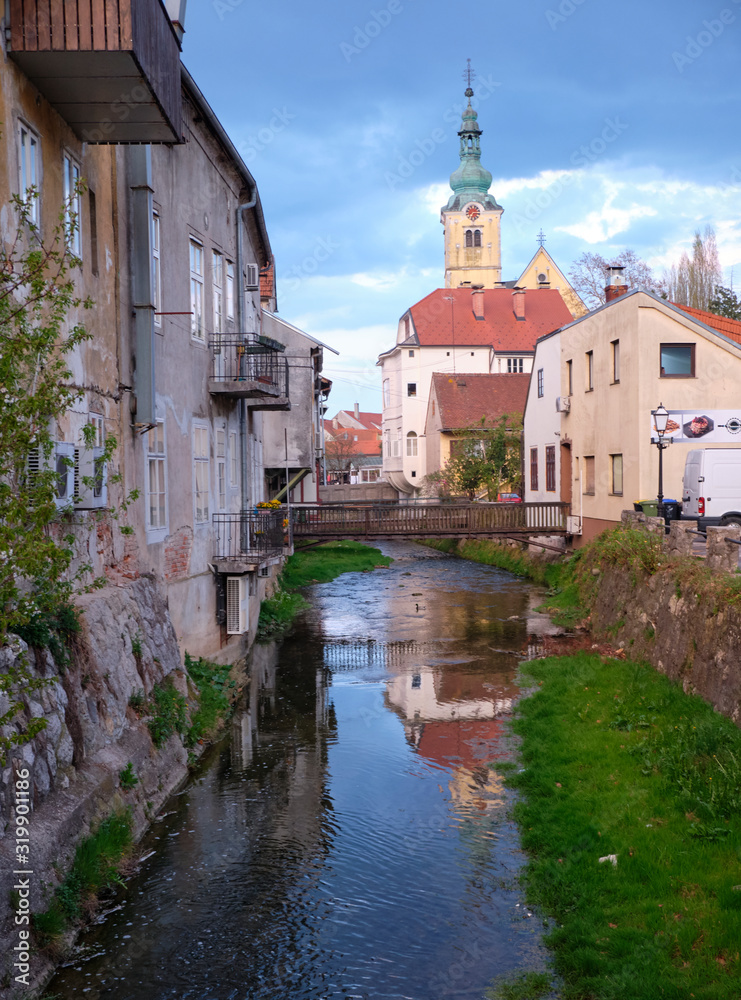 The Gradna river going through Samobor, with houses on side and church tower in backgroung and reflection