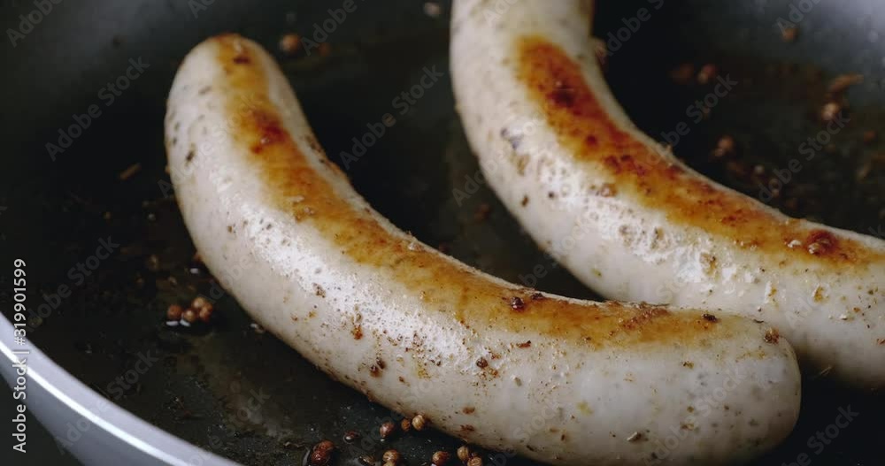 Close-up truck shot of two long bratwurst sausage grilled with Italian mix herb on non-stick pan Close-up truck shot of two long bratwurst sausage grilled with Italian mix herb on non-stick pan