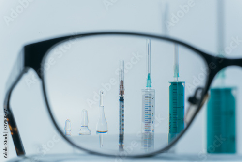 View in glasses. Medicine, Injection, vaccine and disposable syringe isolated, drug concept. Sterile vial medical syringe needle. Macro close up on backgrounds gray. Glass ampoule vial for injection.