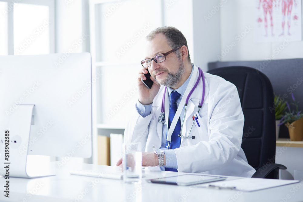 Portrait of senior doctor in office sitting at the desk Portrait of senior doctor in office sitting at the desk