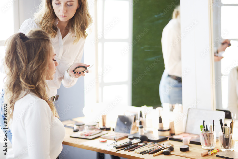 Fototapeta premium make up artist doing professional make up of young woman