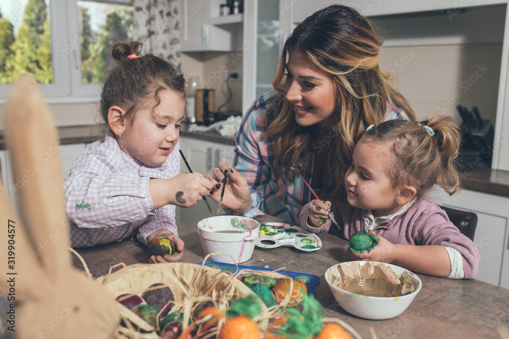 A couple of female children and their mother painting Easter eggs in the kitchen. A couple of female children and their mother painting Easter eggs in the kitchen.