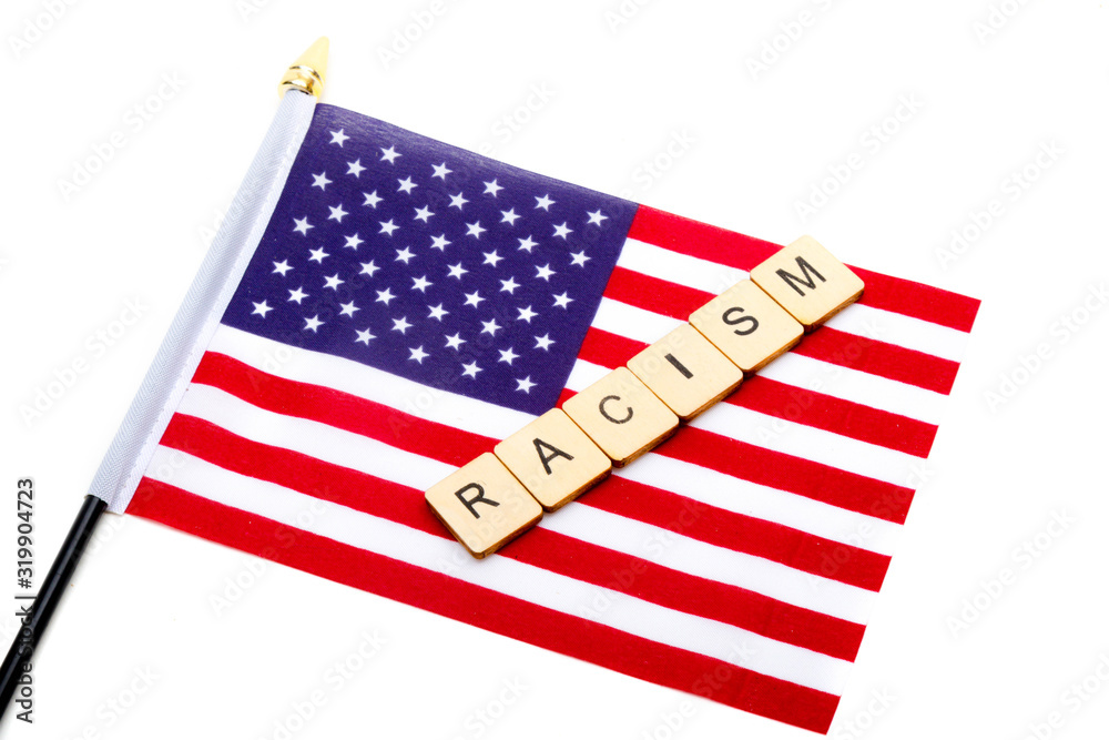 Fototapeta premium The flag of the United States isolated on a white background with a sign reading Racism