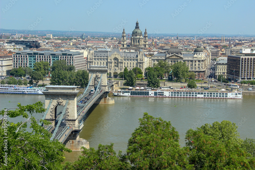 Chain bridge on Danube river. View from the Pest side of the urban landscape panorama of the city with old buildings and domes of opera. Budapest, Hungary.