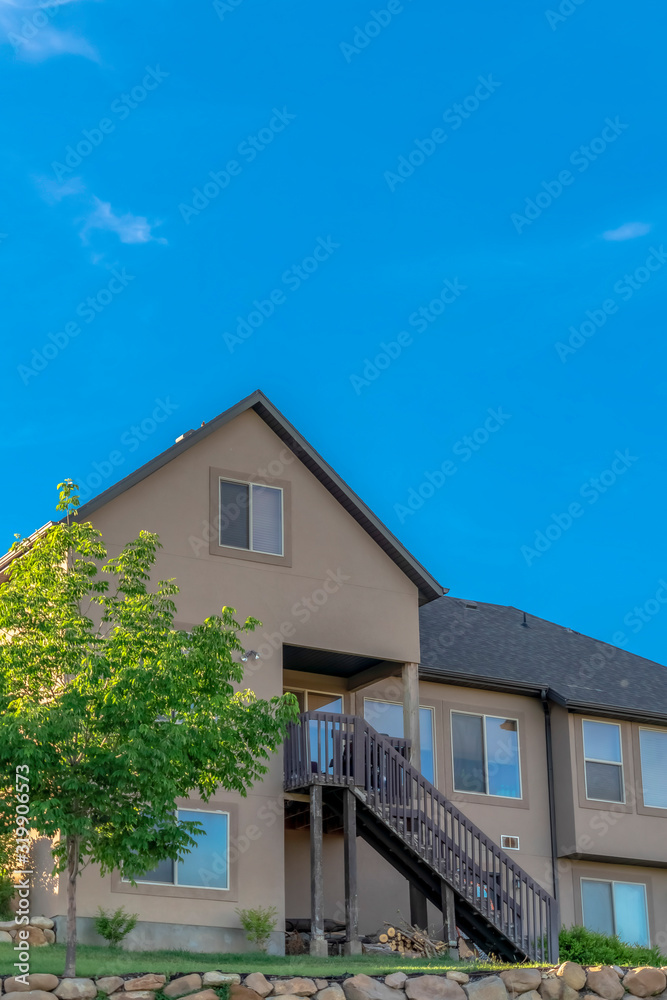 Home exterior with gable and valley roof against vibrant blue sky on a sunny day
