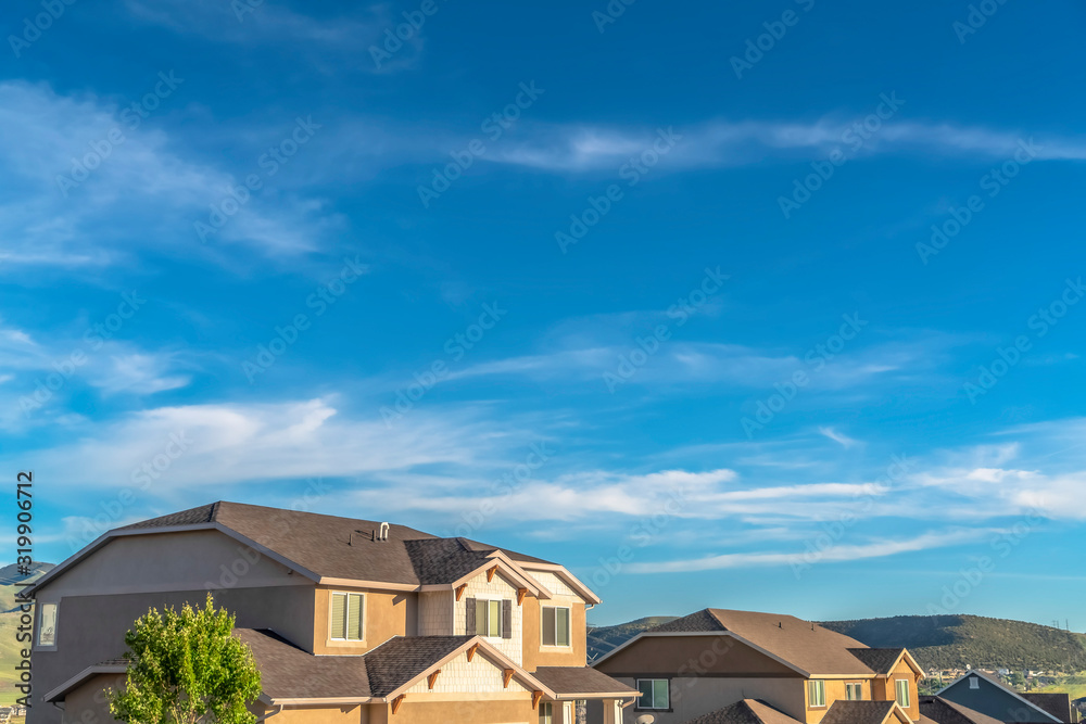 Vibrant blue sky with clouds over houses and hill viewed on a sunny day Vibrant blue sky with clouds over houses and hill viewed on a sunny day