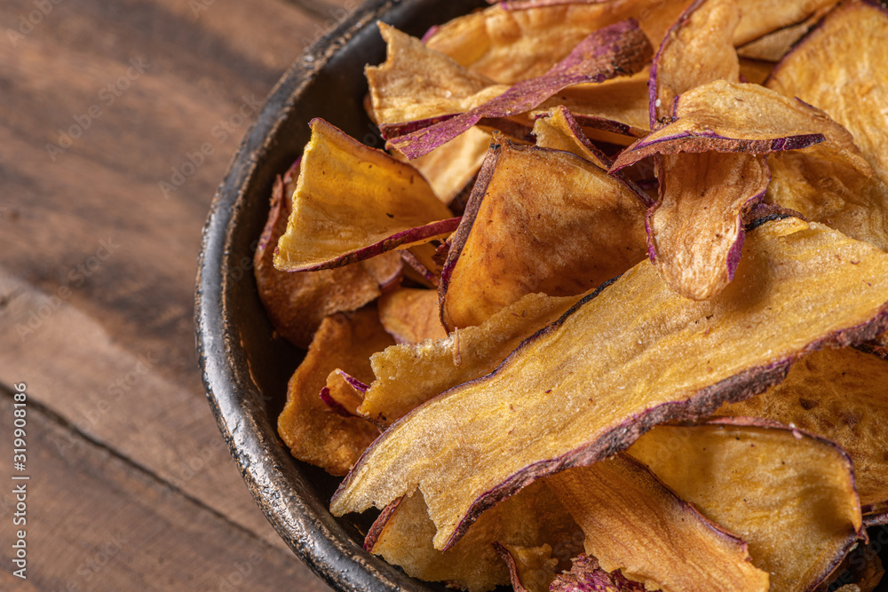 Delicious sweet potato chips in bowl, on table Delicious sweet potato chips in bowl, on table