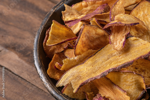 Delicious sweet potato chips in bowl  on table