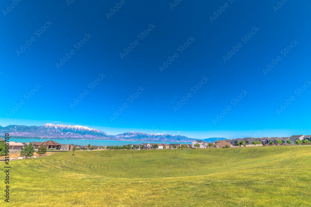 Scenic view of lake mountain homes and sky with golf course in the foreground Scenic view of lake mountain homes and sky with golf course in the foreground