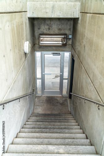 Staircase inside a building going down to a glass door that leads to outdoors