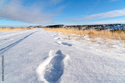 Footprints on fresh white snow covering the road during cold winter season