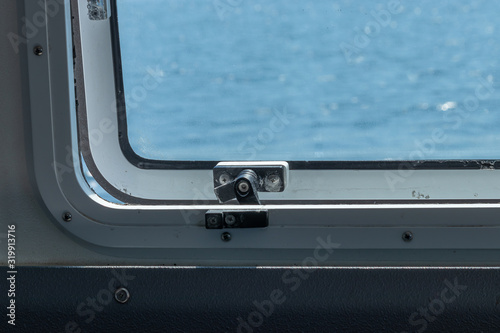 Fototapeta Naklejka Na Ścianę i Meble -  metal latch on a ferry boat window on bright spring day
