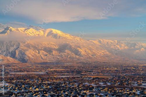 Mount Timpanogos and houses with fresh snow at winter and illuminated by sunset