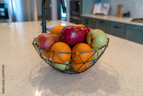 Wired geometric fruit basket with fresh fruits at the kitschen island of home photo