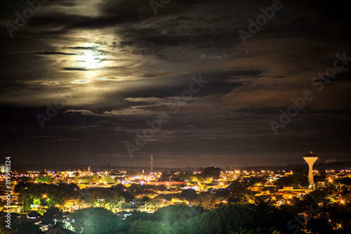 Luar iluminando a cidade em uma noite de nuvens