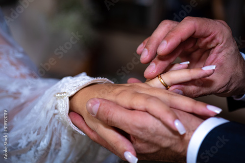 Noivo colocando a aliança no dedo do noiva photo