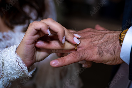 Noiva colocando a aliança no dedo do noivo