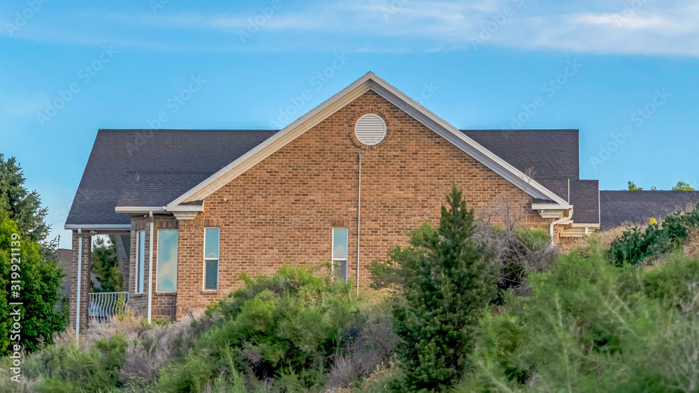 Panorama Blue sky and clouds over a home with gray roof and brick exterior wall